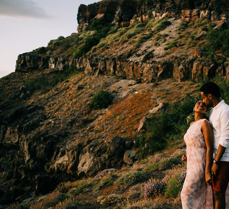 Bride looks back at groom as they stand on the beach during their honeymoon