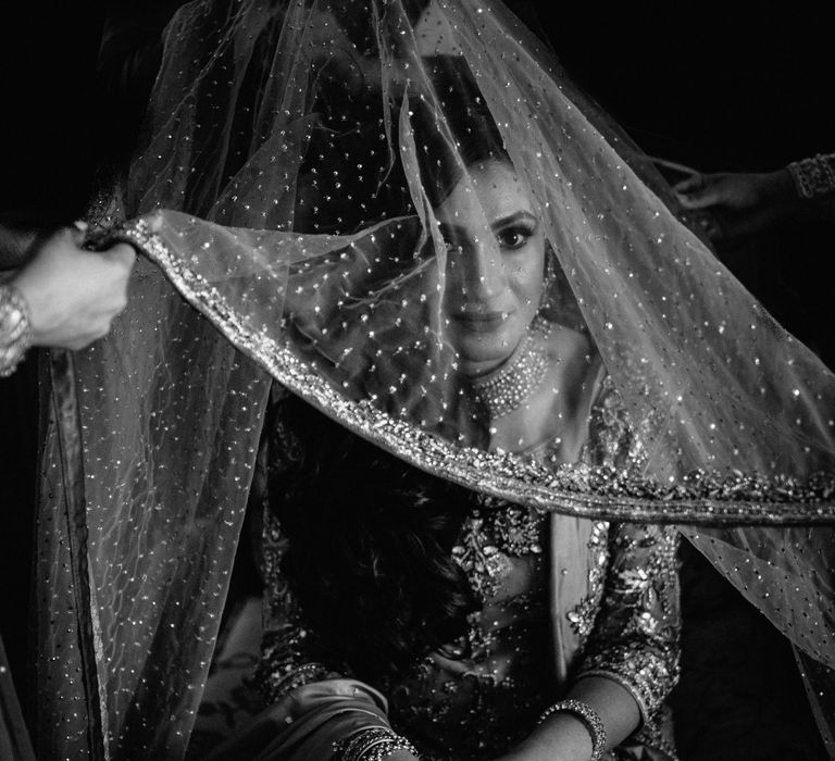 Black & white image of bridal veil being lifted above head