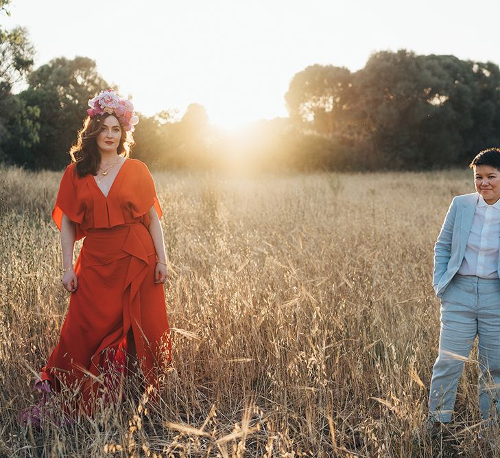 Brides stand apart for post wedding photoshoot as the sun shines behind them during golden hour