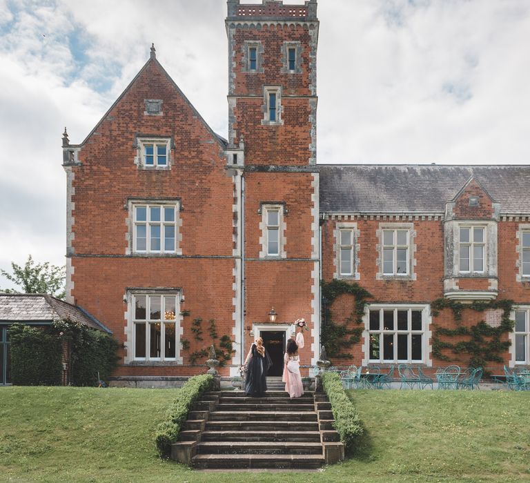 Two brides walking up the steps at Thicket Priory country house wedding venue for Autism marriage inspiration