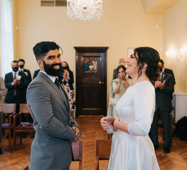 Bride & groom smile lovingly at one another during their civil ceremony on their wedding day at Chelsea Old Town Hall