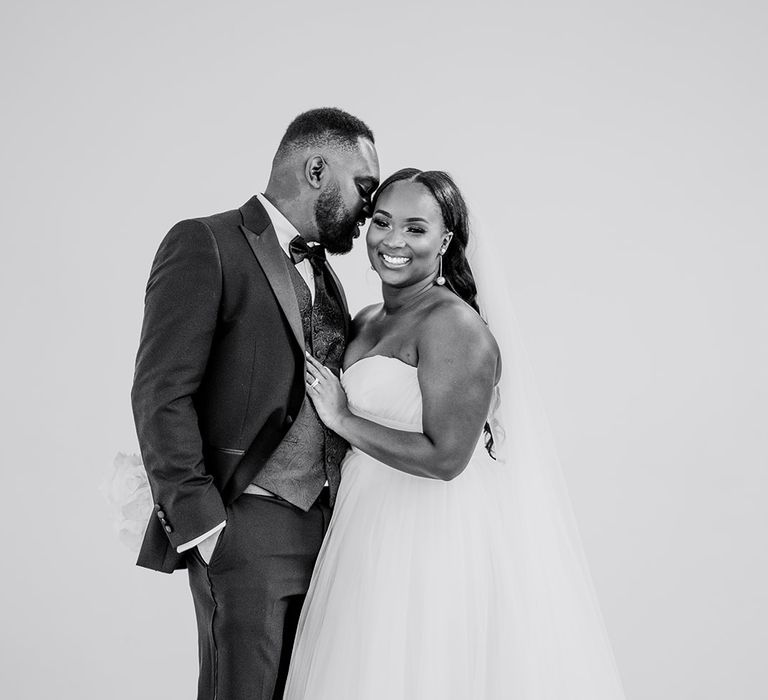 Bride & groom stand with one another as bride wears sweetheart neckline full skirt gown and hair in loose natural curls