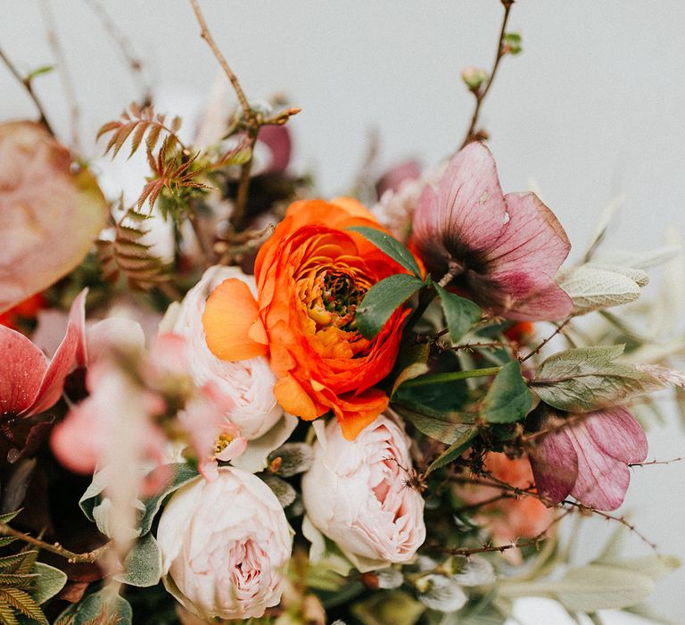 Pink, orange and red wedding bouquet with foliage,  ranunculus and spay roses