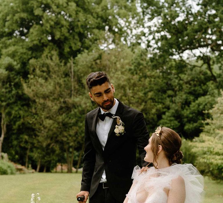 Portrait of the groom in a tuxedo looking at his bride in a tulle wedding dress as she sits in her wheelchair 