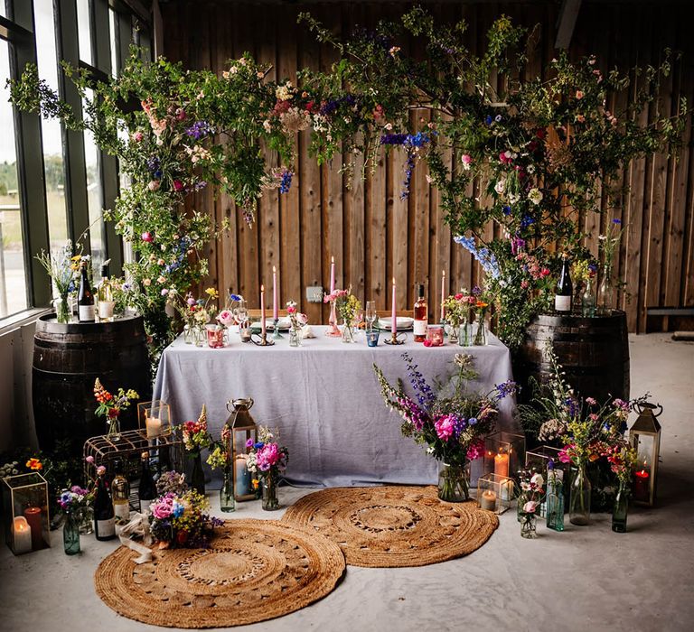 Sweetheart table decorated with wicker rugs, barrels and wildflower installation 