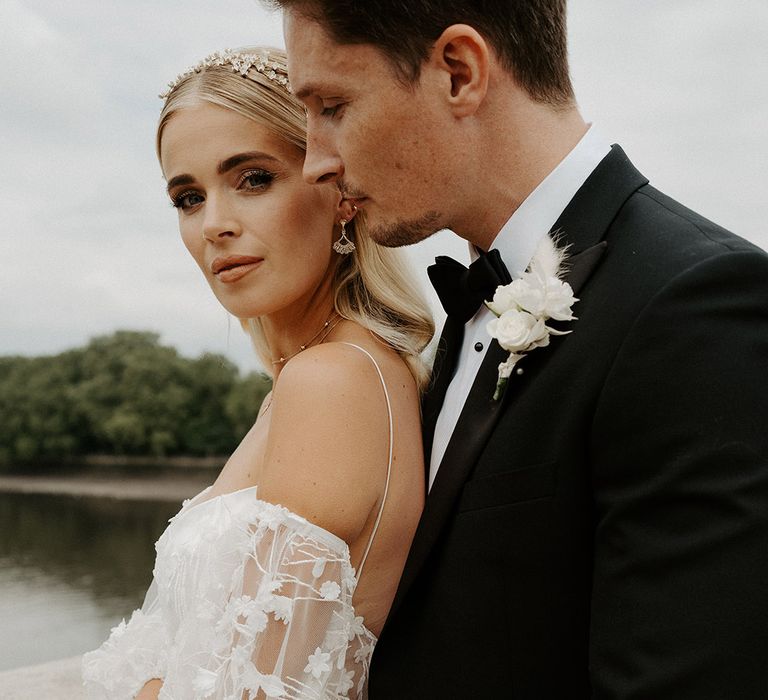 Blonde bride with natural makeup up and slick back hair wearing a wedding dress with lace detachable sleeves