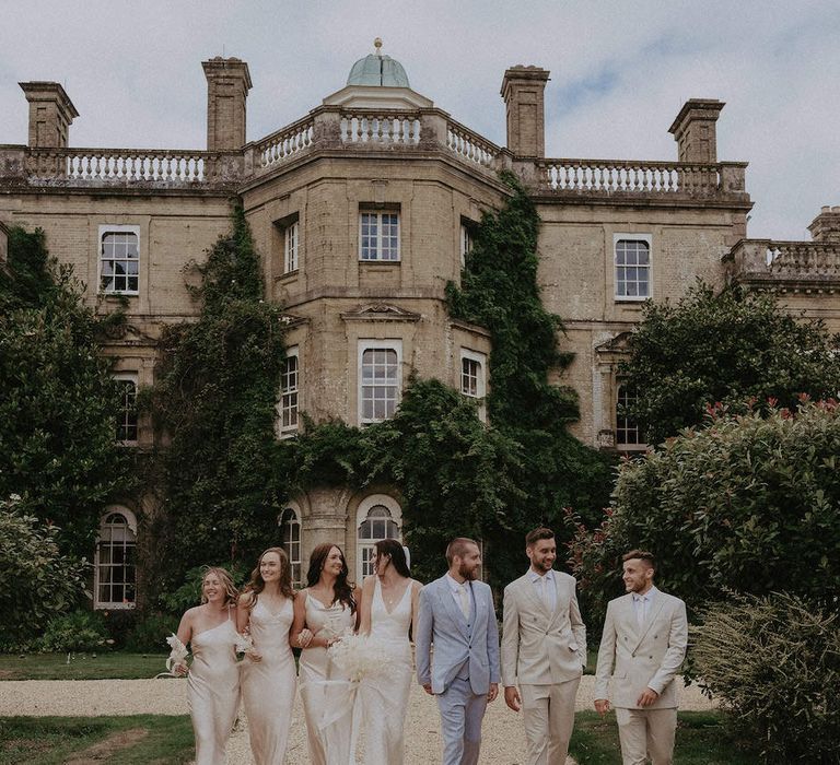 Bridesmaids in champagne dresses with groomsmen in cream wedding suits