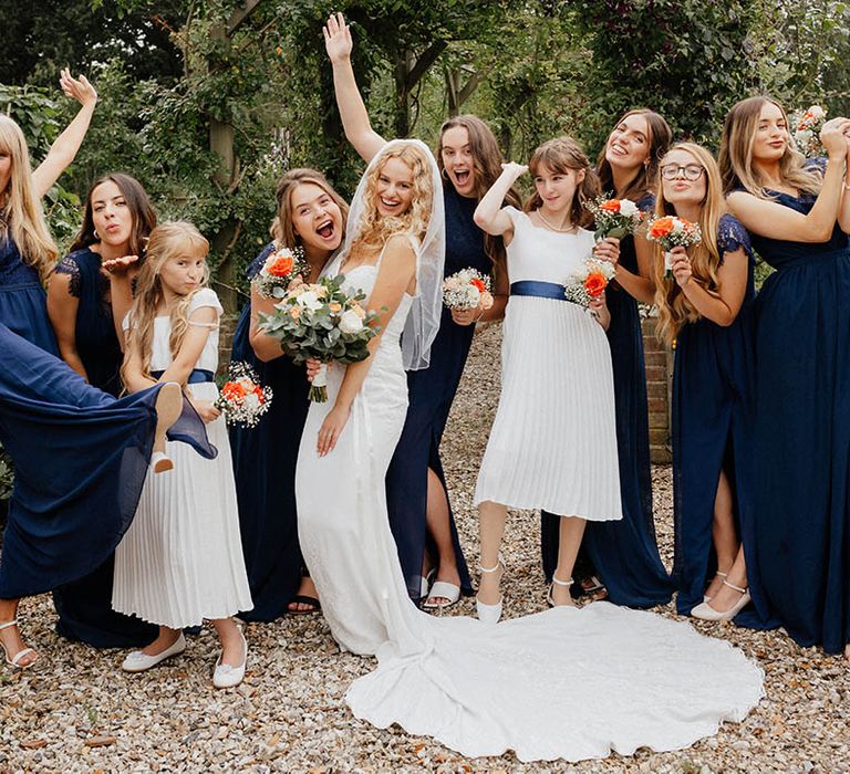 Bride poses with her bridesmaids who wear royal blue bridesmaids dresses from depop