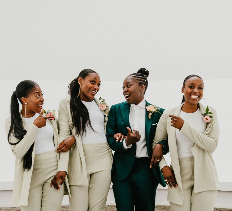 Black bride in a green suit with her bridesmaids in beige suits 