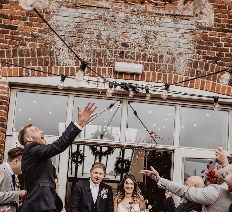 Bride & groom walk through confetti as wedding guests throw around them