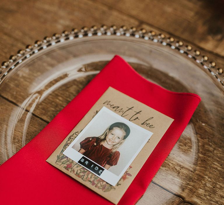 Place setting glass charger plate, red napkin and polaroid picture name place card 