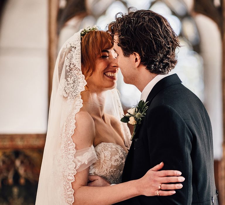 Bride in off the shoulder wedding dress kisses groom at Oxnead Hall wedding