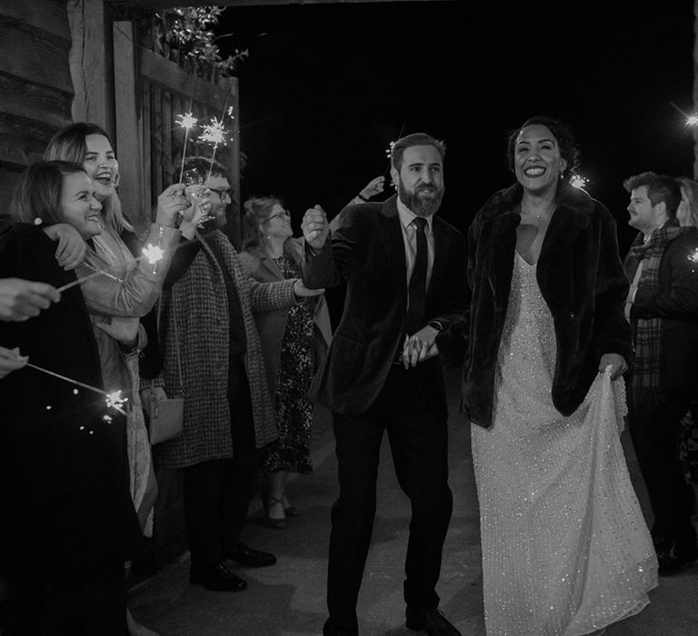 Bride & groom walk through sparkler exit on their wedding day in black & white image