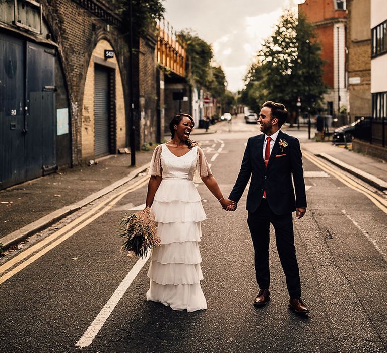 golden hour bride and groom portrait in London with Black bride in a layered tulle wedding dress and groom in a navy blue suit 