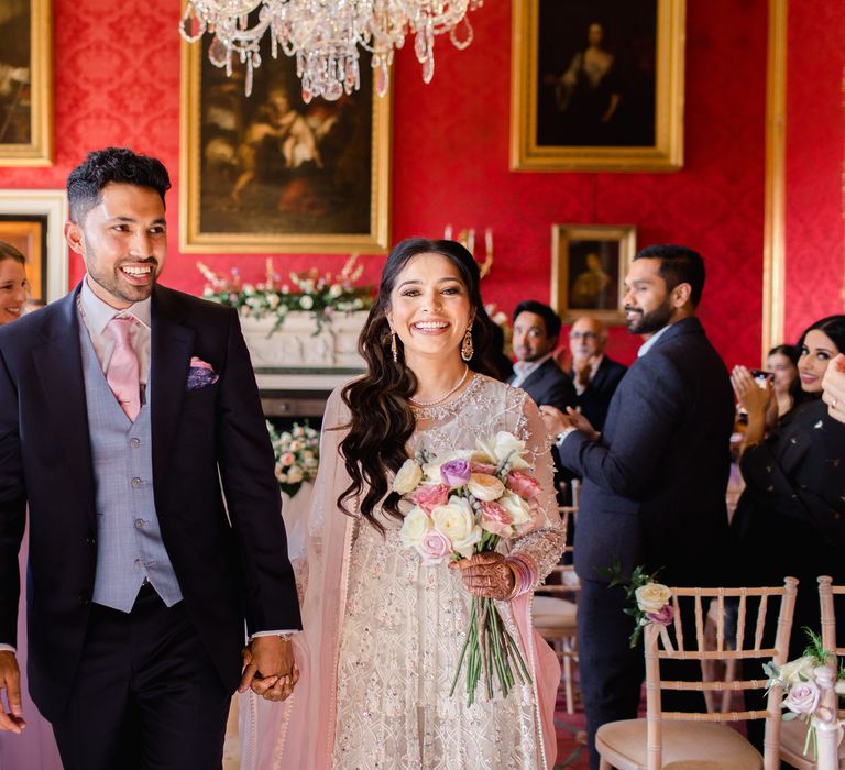 Bride & groom walk with one another hand in hand after their wedding ceremony