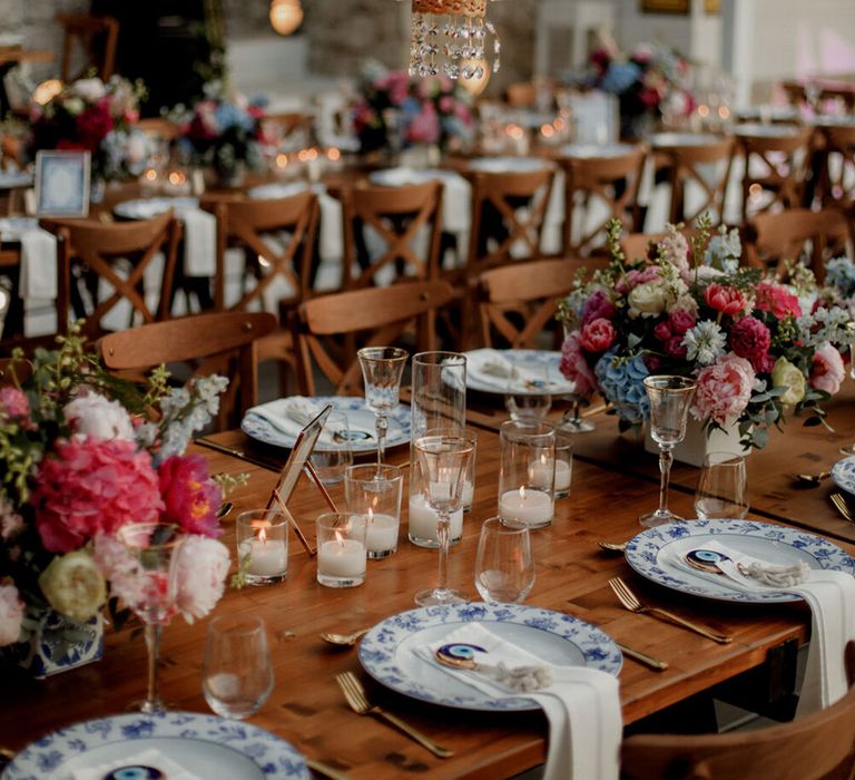 Chandelier hangs above wooden tables complete with bright florals 