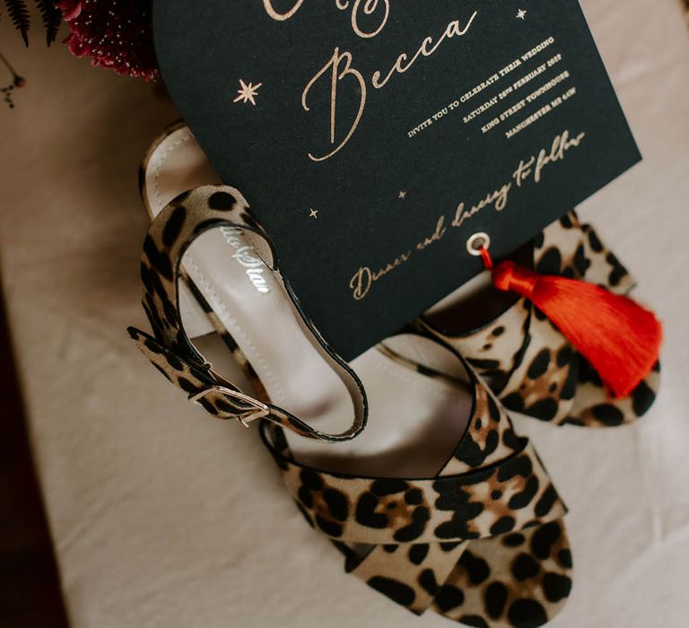 Black wedding invitation with gold foil lettering and red tassel 