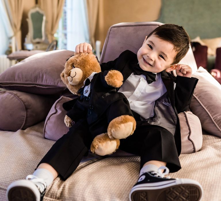 Little wedding guest in black tie with teddy bear also wearing a black tie outfit 