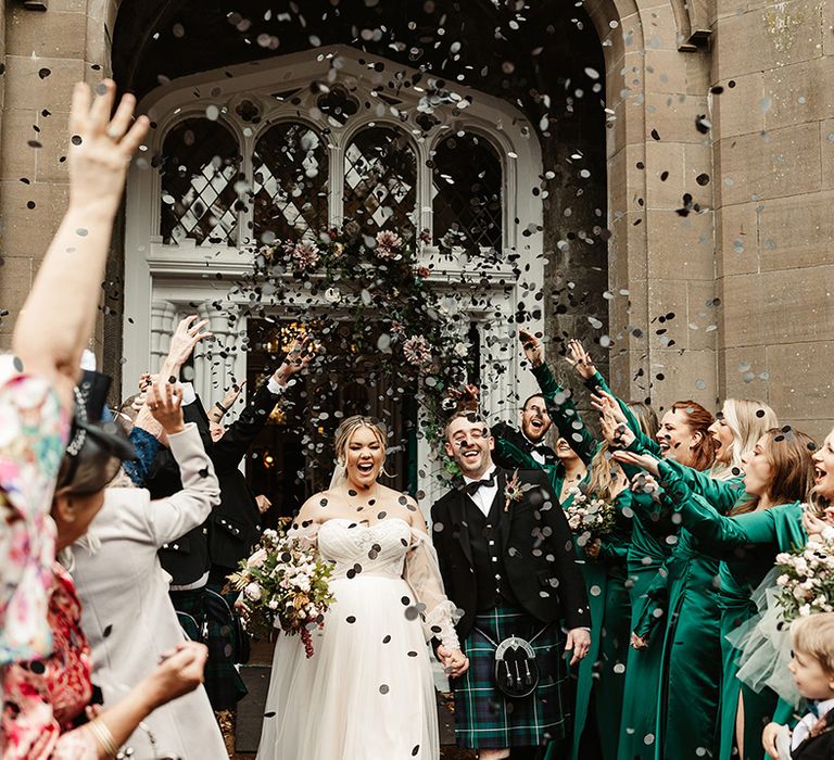 Wedding guests cheer and celebrate by throwing black circle confetti for the newlyweds