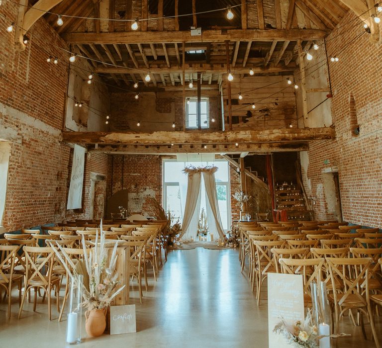 Barn wedding venue with wedding drapes, dried flowers, candles and unplugged ceremony sign for boho decor wedding