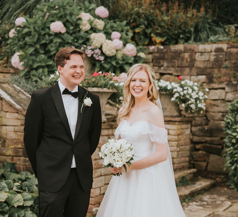 Bride in off the shoulder wedding dress with ballgown skirt with brother in black tie 