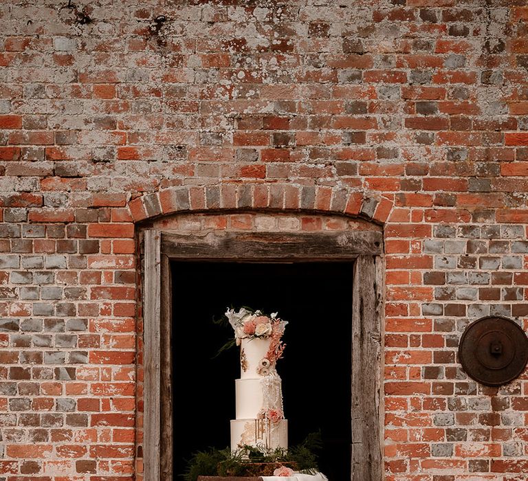 three tier wedding cake with flower cake topper on a wooden barrel cake stand at Mapledurham wedding venue n Oxfordshire 