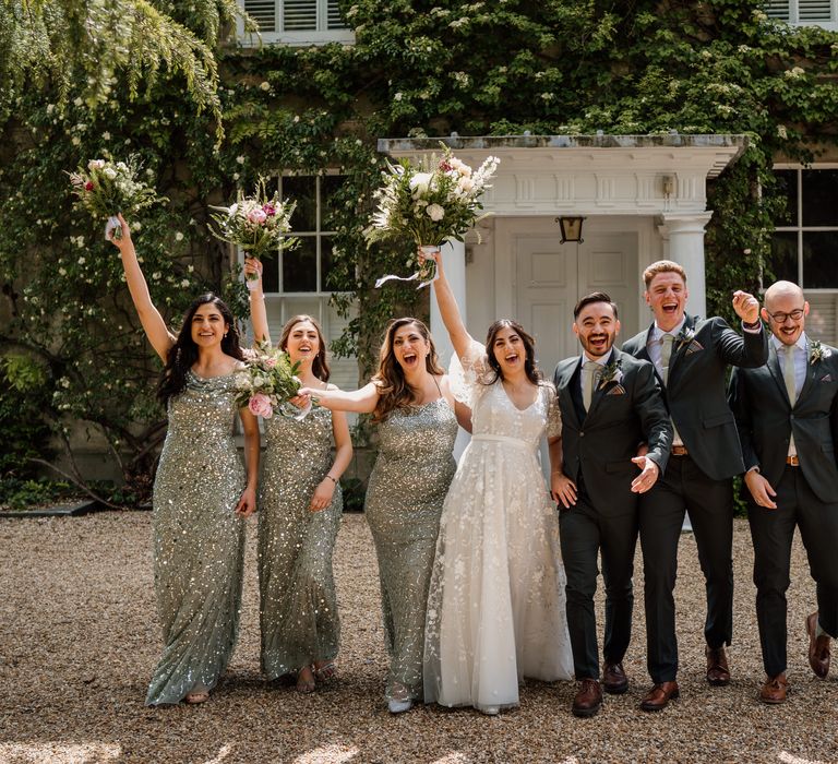 Bride wears Anna Campbell boho dress with floral embellishment whilst stood with her bridesmaids wearing sparkly green bridesmaid dresses