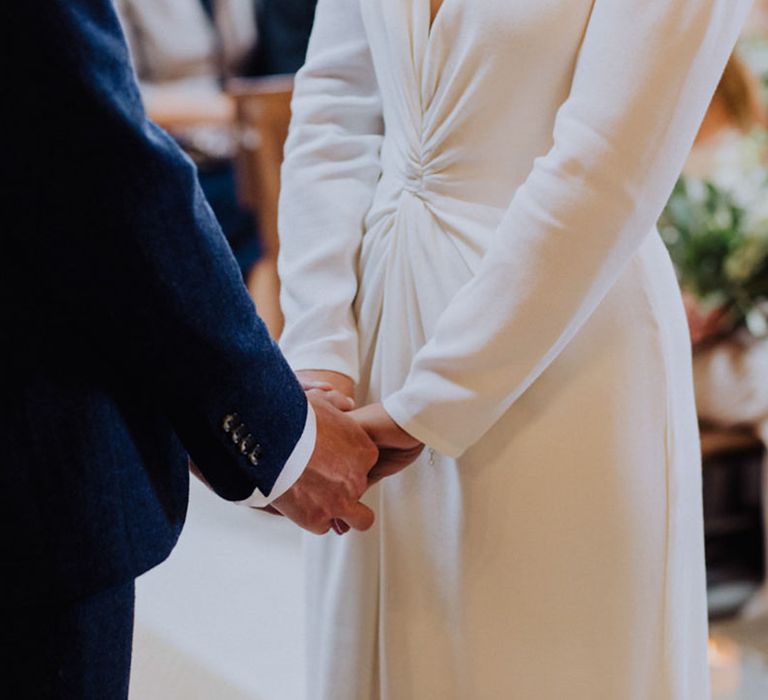 Bride and groom hold hands during their wedding ceremony at The Barn at Botley Hill