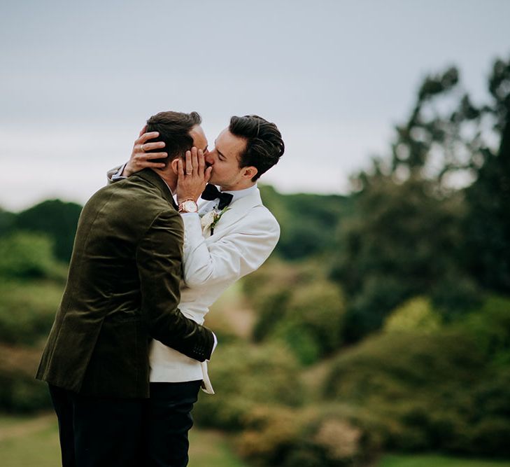 Grooms kiss outdoors in front of rolling hills at Birdsall House 