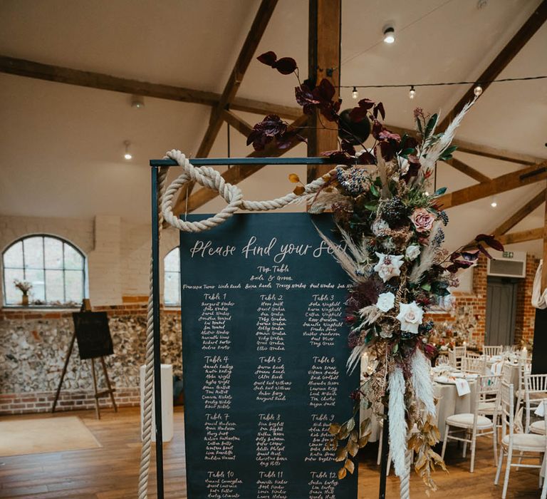 Black wedding table plan/seating chart sign decorated with rope and autumnal wedding flowers 