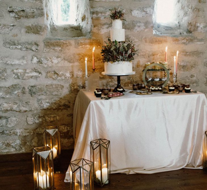 Wedding cake table decorated with candles, lanterns and acrylic signs 