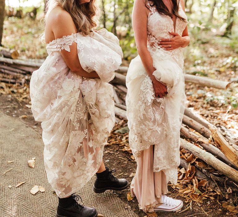 Brides walk in their woodland setting lifting their dresses to show off their flat shoes 