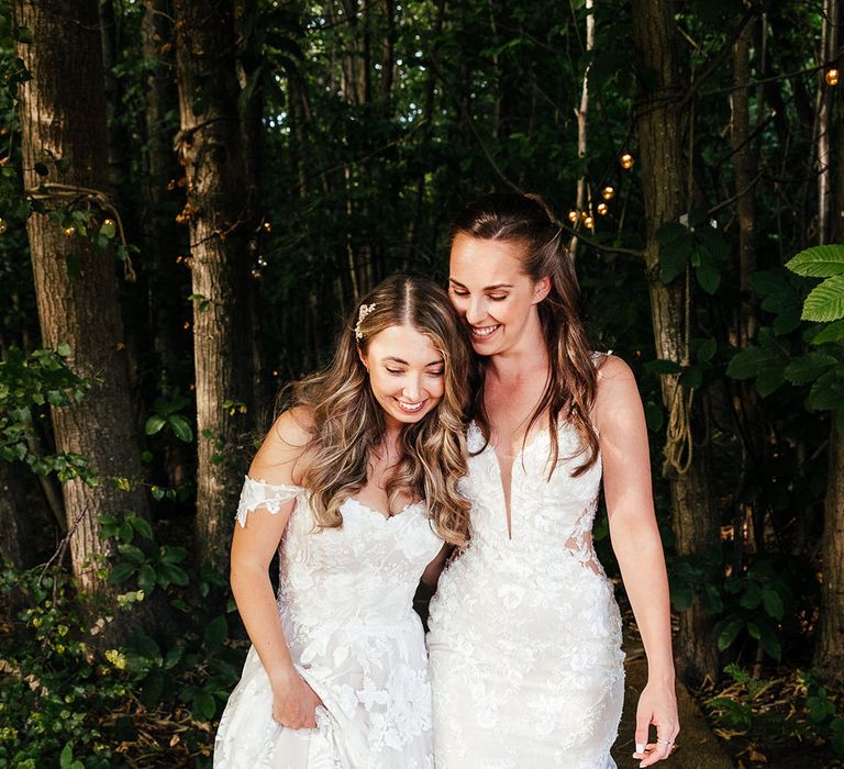 Brides walk closely together in boho wedding gowns for their wedding at The Dreys