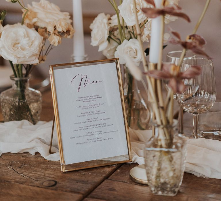 Romantic table setting with pink and white flowers and candles with gold photo frame menu