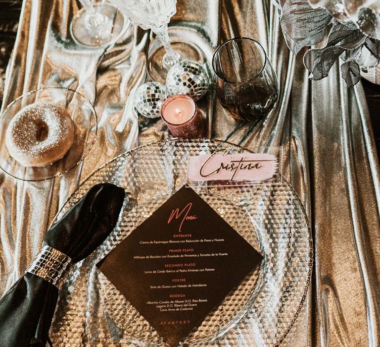 Sparkly wedding tablescape with disco balls, sparkly doughnuts and flowers, metallic table cloth and mirrored napkin rings 