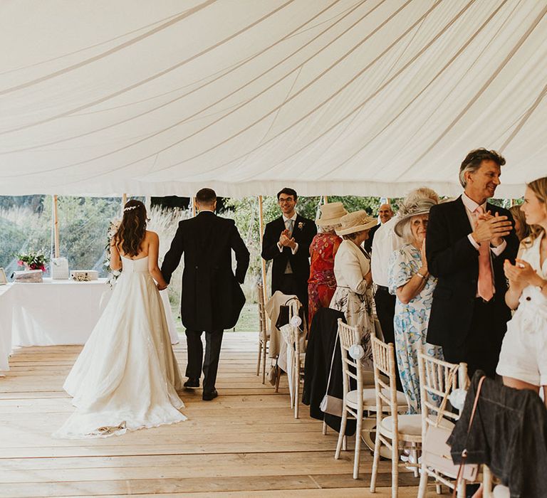 Bride and groom enter their white marquee wedding reception 