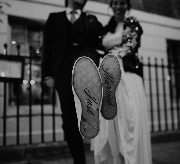 Bride and groom wearing matching customised converse with "just married" written on the soles 