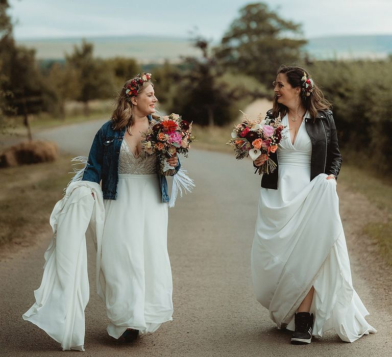 Bride in Freda Bennet wedding dress walking with bride with them both wearing customised bridal cover ups 