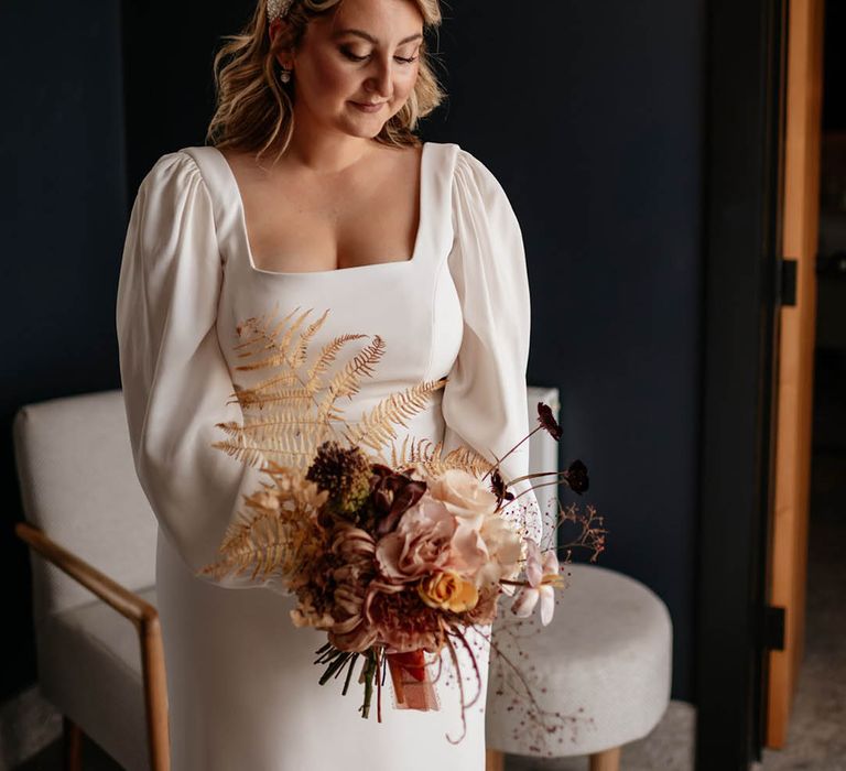 Bride in square neck wedding dress with puff sleeves with a chunky pearl headband and neutral wedding bouquet 