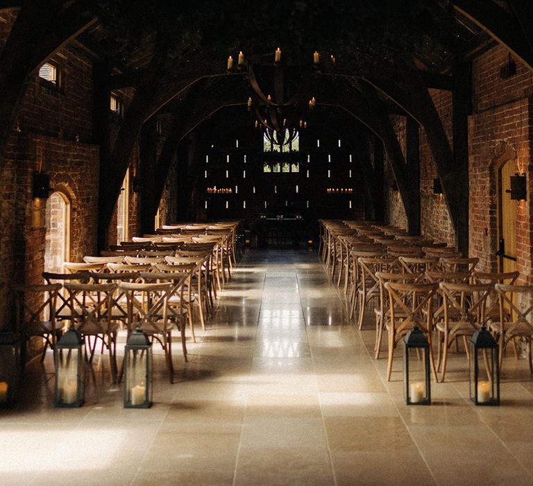 Rustic barn Grangefields wedding venue with tall vintage black lanterns and wooden chairs for that cosy feeling 