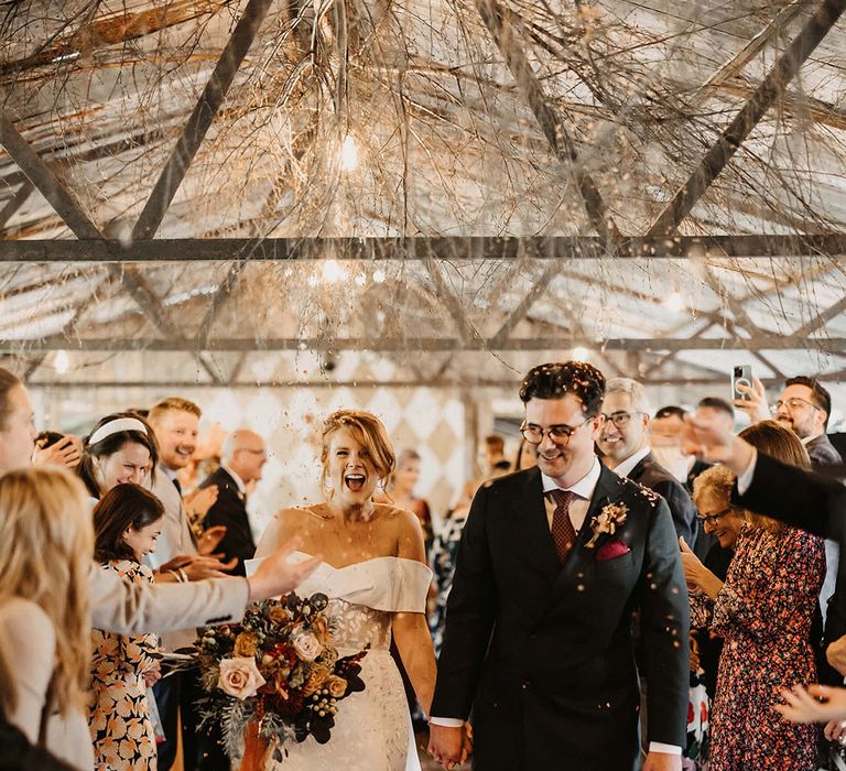 Bride walks through colourful confetti exit with her groom after bespoke wedding ceremony at The Dreys