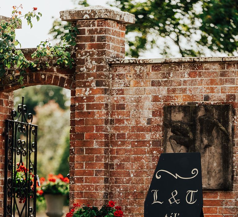 Black and gold coffin wedding welcome sign at the entrance to Parley Manor wedding venue 