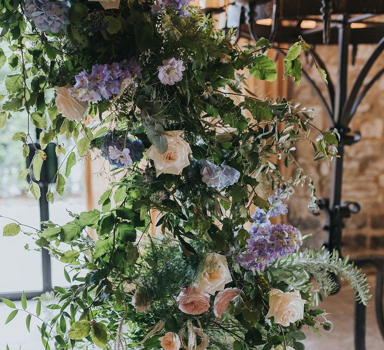 pastel pink rose and blue thistle wedding flowers on floral arch 