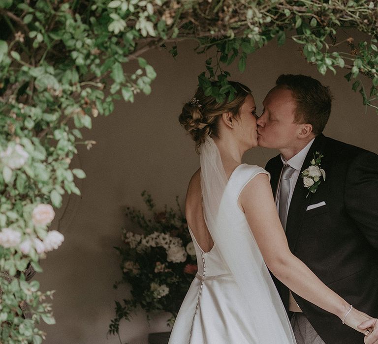 The bride and groom share their first kiss as a married couple at their hotel wedding venue 