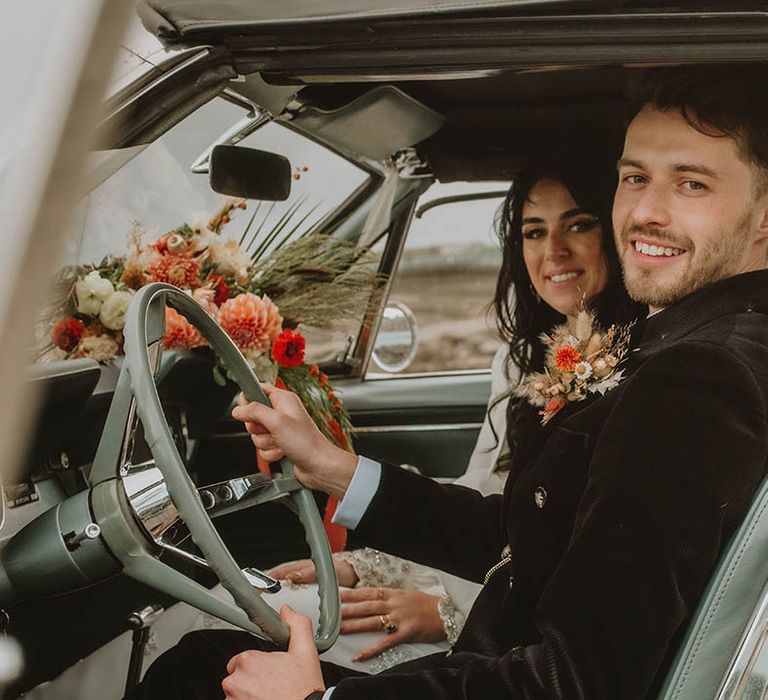 Groom in black suit with dried flower buttonhole riding in the wedding car with the bride for retro wedding 