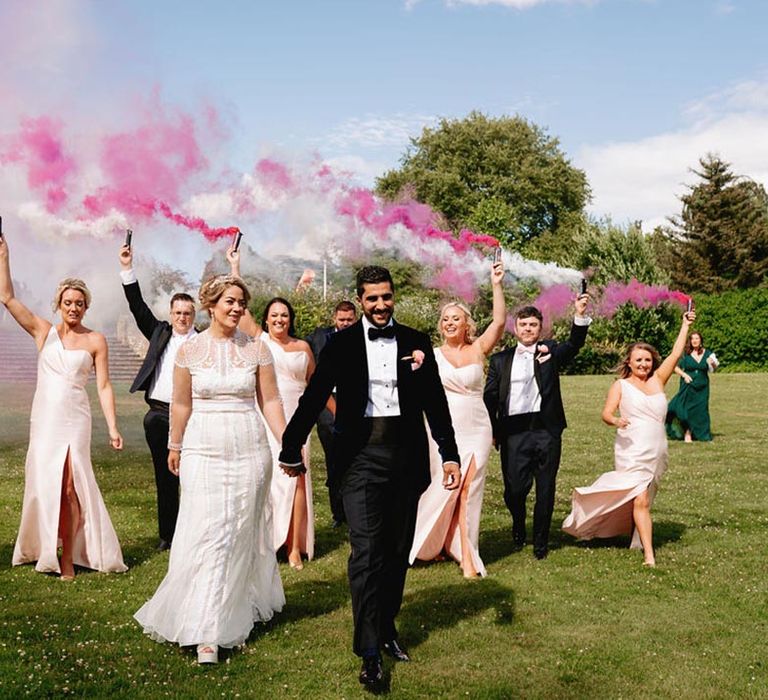 Pink and white colourful smoke bomb wedding photo with the whole wedding party in pink theme outfits 