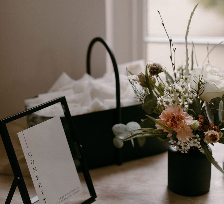 Black basket of wedding confetti with personalised pouches of confetti 