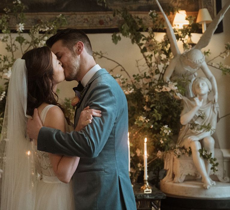 Groom in blue velvet blazer kissing the bride for their first kiss as a married couple 