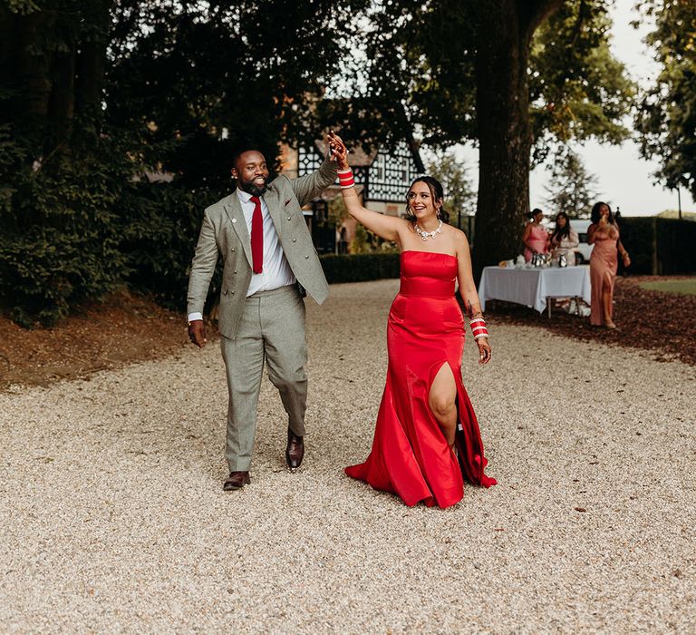 The bride and groom re enter their wedding reception in new bright and bold wedding reception outfits 