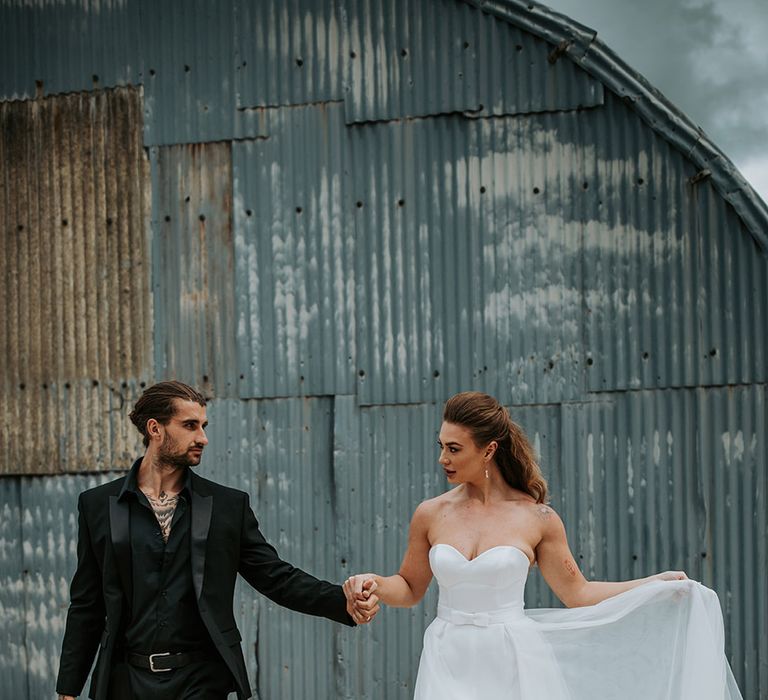 Groom in black wedding suit and shirt with bride in strapless wedding outfit with bow 